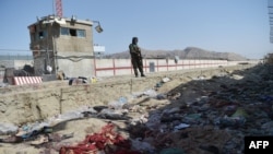 A Taliban fighter stands guard at the site of the Aug. 26 suicide bombing, which killed scores of people including 13 US troops, at Kabul airport on Aug. 27, 2021.