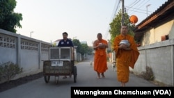 Buddhist monks at Pa Book Temple in Lamphun, Thailand, use a mobile food cabinet to collect alms.