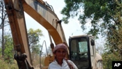 Puth La, 62, an ethnic minority Suy woman, standing next to a digger that villagers say is being used by a Singaporean company to destroy thousands of hectares of land they claim as their own in the province of Kampong Speu, south-west of the capital Phno