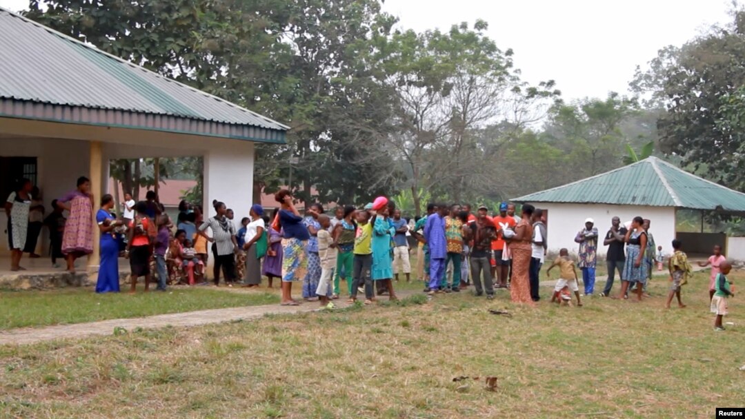 FILE - A still image taken from a video shot on Dec. 9, 2017, shows Cameroonian refugees standing outside a center in Agbokim Waterfalls village, Nigeria, near the country's border with Cameroon.