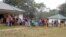FILE - A still image taken from a video shot on Dec. 9, 2017, shows Cameroonian refugees standing outside a center in Agbokim Waterfalls village, Nigeria, near the country's border with Cameroon.