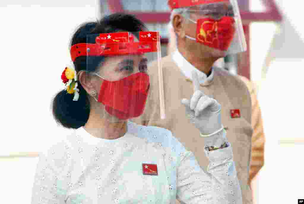 Myanmar leader Aung San Suu Kyi wearing a face shield, mask and gloves, gestures during a flag-raising ceremony to mark the first day of election campaign at the National League for Democracy party&#39;s temporary headquarters in Naypyitaw.