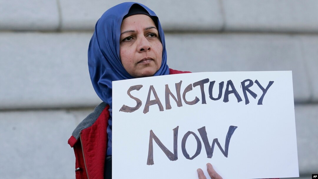 FILE - Moina Shaiq holds a sign at a rally outside of City Hall in San Francisco, Jan. 25, 2017.
