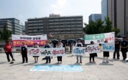 Protesters stand with banners to oppose planned joint military exercises between South Korea and the United States near the U.S. embassy in Seoul, South Korea, Monday, Aug. 5, 2019.