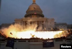 FILE - An explosion caused by a police munition is seen while supporters of U.S. President Donald Trump gather in front of the U.S. Capitol Building in Washington, Jan. 6, 2021.
