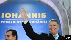 Romanian President Klaus Iohannis, right, waves next to Romanian prime minister Ludovic Orban, after exit polls were published, in Bucharest, Romania, Nov. 24, 2019. 