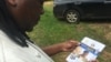 A man reading a Reserve Bank of Zimbabwe flyer promoting the use of plastic money to ease the country's over-a-year problem of cash shortages, Gokwe, Zimbabwe, Jan. 31, 2017. (S. Mhofu/VOA)