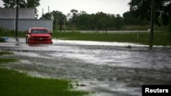 Sebuah mobil melewati jalanan yang terendam banjir di dekat Vermilion Bay akibat Badai Laura yang bergerak mendekati Abbeville, Louisiana, AS, 26 Agustus 2020.