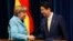 Germany's Chancellor Angela Merkel (L) shakes hands with Japan's Prime Minister Shinzo Abe