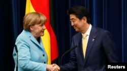 Kanselir Jerman Angela Merkel (kiri) berjabat tangan dengan PM Jepang Shinzo Abe seusai konferensi pers di Tokyo (9/3).