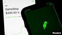 Trading information for GameStop is displayed on the Robinhood App as another screen displays the Robinhood logo in this photo illustration January 29, 2021. REUTERS/Brendan McDermid/Illustration