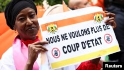 (FILE) A demonstrator holds a placard reading "We don't want a coup anymore" outside Niger's embassy in France.