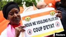 FILE - A demonstrator holds a placard reading "We don't want a coup anymore" outside Niger's embassy in support of the President of Niger Mohamed Bazoum in Paris, France, August 5, 2023