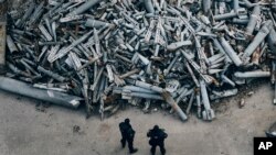 ARCHIVO - Oficiales de policía observan fragmentos recolectados de los cohetes rusos, incluidas bombas de racimo, que impactaron en Kharkiv, en Kharkiv, Ucrania, el 3 de diciembre de 2022.