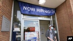 A customer walks out of a U.S. Post Office branch and under a banner advertising a job opening, in Seattle, June 4, 2020.