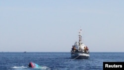 FILE - A Vietnamese sinking boat (L) which was rammed and then sunk by Chinese vessels near disputed Paracels Islands, is seen near a Marine Guard ship (R) at Ly Son island of Vietnam's central Quang Ngai province.