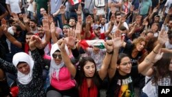 Anti-government protesters shout slogans as they block a main highway, in Beirut, Lebanon, Saturday, Oct. 26, 2019. 