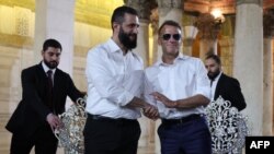 France's President Emmanuel Macron (R) shakes hands with Syrian President Ahmed Al-Charaa during a visit to the Umayyad Mosque in Damascus, on July 6, 2026.