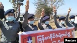 Para polisi membentangkan spanduk dan mengacungkan salam tiga jari untuk memprotes kudeta militer di negara bagian Kayah, Myanmar, 10 Februari 2021. (Foto: Khun Bwe Mue via Reuters)