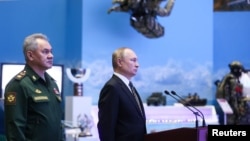 Presiden Rusia Vladimir Putin (kanan) dan Menhan Sergei Shoigu menghadiri pameran kekuatan militer Rusia di Moskow (21/12). 