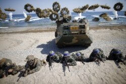 FILE - South Korean (blue headbands) and U.S. Marines take positions as amphibious assault vehicles of the South Korean Marine Corps fire smoke bombs during a U.S.-South Korea joint landing operation drill in Pohang, South Korea, March 12, 2016.