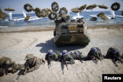 FILE - South Korean (blue headbands) and U.S. Marines take positions as amphibious assault vehicles of the South Korean Marine Corps fire smoke bombs during a U.S.-South Korea joint landing operation drill in Pohang, South Korea, March 12, 2016.