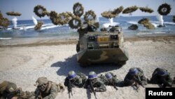 FILE - South Korean (blue headbands) and U.S. Marines take positions as amphibious assault vehicles of the South Korean Marine Corps fire smoke bombs during a U.S.-South Korea joint landing operation drill in Pohang, South Korea, March 12, 2016. 