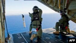 Dua perwira Angkatan Udara Australia Sersan Adam Roberts (kiri) dan Sersan Angkatan Udara John Mancey (kanan), bersiap untuk meluncurkan Penanda Data "Buoy" dari pesawat Hercules C-130J di wilayah Samudera Hindia untuk membantu pencarian pesawat Malaysia MH370 (20/3).