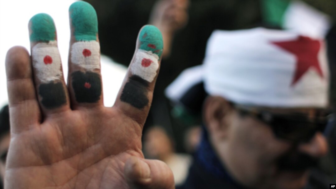 An anti-Syrian regime protester colors his fingers with the revolutionary flag colors during a protest outside the Arab League headquarters in Cairo, Egypt Sunday, Jan. 22, 2012.