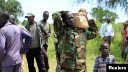 An armed man carries boxes with forms delivered by members of Joint Military Ceasefire Commission (JMCC), meant to select soldiers from the opposition and the government into the South Sudanese military.