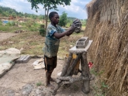 Fourteen-year-old Musa Ssewanyana, a high school student, drops a mold of clay sand preparing to lay bricks in Ntawo village, Mukono district, Uganda, Aug. 1, 2020. (Halima Athumani/VOA)