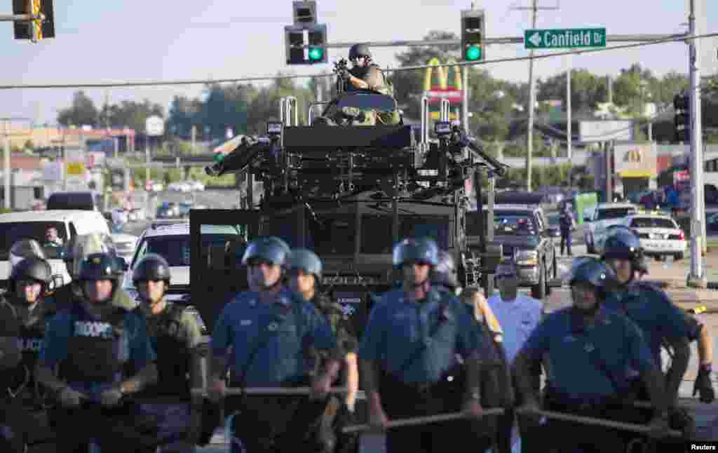 Riot police stand guard as demonstrators protest the shooting death of teenager Michael Brown, in Ferguson, Missouri Aug. 13, 2014.