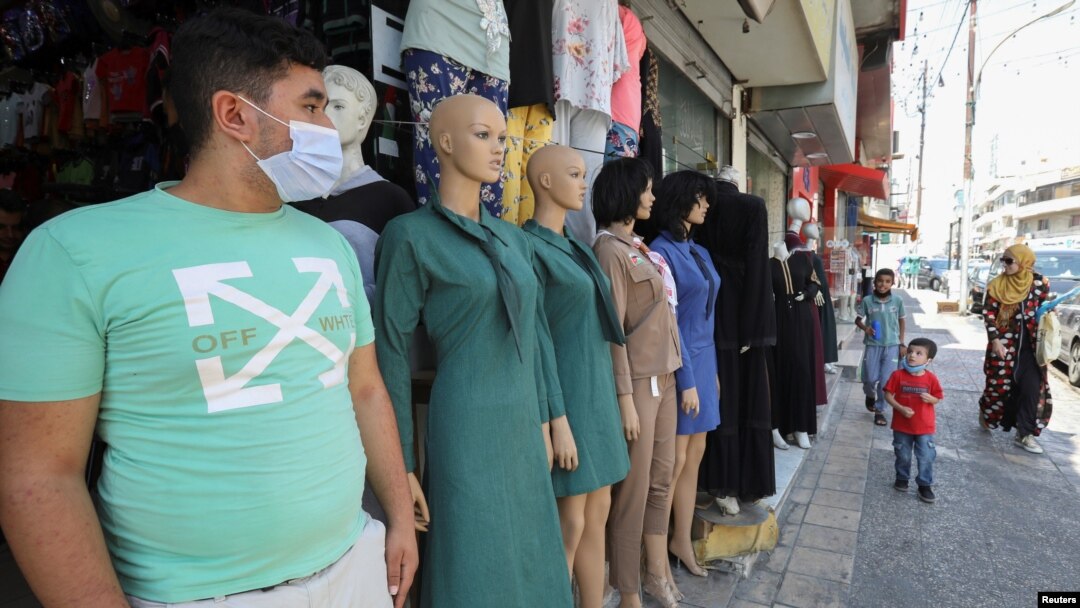 A vendor wearing a face mask stands in front of his school uniform shop, ahead of the first day of the new school year, amid fears of rising number of the COVID-19 cases in Amman, Jordan, Aug. 31, 2020.