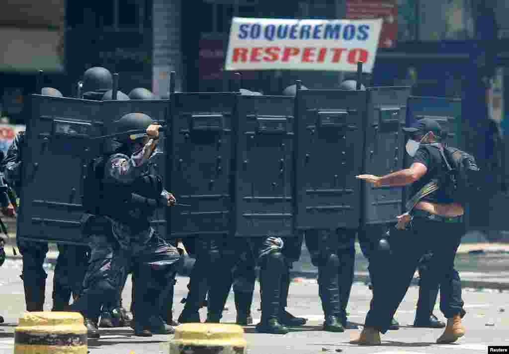A man clashes with riot police during a civil servant protest against the Rio de Janeiro state government and a plan that will limit public spending, in front of the State Assembly of Rio de Janeiro, Brazil.