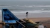 FILE - A man walks holding an umbrella during a drizzle at the Puri beach on the Bay of Bengalcoast in Odisha, India, May 24, 2021. The area was bracing for another storm, Cyclone Dana, on October 22, 2024.