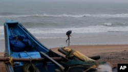 FILE - A man walks holding an umbrella during a drizzle at the Puri beach on the Bay of Bengalcoast in Odisha, India, May 24, 2021. The area was bracing for another storm, Cyclone Dana, on October 22, 2024.