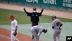In this Tuesday, May 5, 2020, file photo, first base umpire Lee Ki-joong, wearing a mask and gloves as a precaution against the new coronavirus, makes a call during a baseball game between Hanwha Eagles and SK Wyverns in Incheon, South Korea.