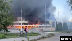 Smoke and flames rise from a shopping center damaged by shelling in the course of the Russia-Ukraine conflict, in Donetsk, Russian-controlled Ukraine, in this screengrab taken from a video released on Aug. 16, 2024. 