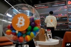 FILE - An employee watches an electronic signboard displaying the prices of bitcoin and other cryptocurrencies at the lounge of Bithumb cryptocurrency exchange in Seoul, South Korea, Nov. 21, 2024.