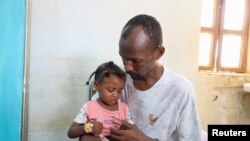 FILE-Man carries his daughter at a medical health center in Omdurman, Sudan, September 3, 2023. REUTERS/El Tayeb Siddig