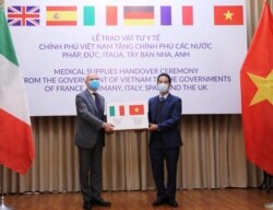 FILE - Vietnam's Deputy Foreign Minister To Anh Dung hands a box of protective masks to Italy's Ambassador to Vietnam Antonio Alessandro as Vietnam donates medical supplies to Europe amid the coronavirus pandemic, in Hanoi, Vietnam, April 7, 2020.