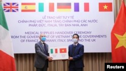 FILE - Vietnam's Deputy Foreign Minister To Anh Dung (right) hands a box of protective masks to Italy's Ambassador to Vietnam Antonio Alessandro during a handover ceremony as Vietnam donated supplies to European countries, in Hanoi, Vietnam, April 7, 2020.