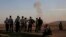 Turkish Kurds watch as airstrikes hit Kobani, inside Syria, as fighting intensifies between Syrian Kurds and the militants of Islamic State group, in Mursitpinar, on the outskirts of Suruc, at the Turkey-Syria border, Wednesday, Oct. 8, 2014.