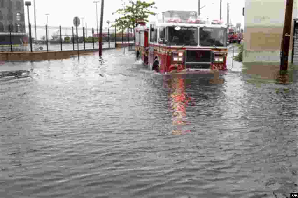 A fire truck drives through a flooded street in Brooklyn, New York, Sunday, Aug. 28, 2011. Seawater surged into the streets of Manhattan on Sunday as Tropical Storm Irene slammed into New York, downgraded from a hurricane but still unleashing furious win