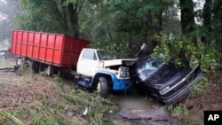 A truck and a car sit in a creek, Aug. 22, 2021, after they were washed away the day before in McEwen, Tennessee.