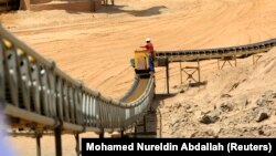 Seorang pekerja berfoto di samping ban berjalan di tambang Sudan, 28 September 2011. (Foto: REUTERS/Mohamed Nureldin Abdallah)