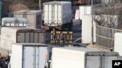 South Korean cargo trucks head to the North Korean city of Kaesong as South Korean Army soldiers stand guard at the customs, immigration and quarantine office near the border village of Panmunjom in Paju, South Korea, Feb. 11, 2016. 