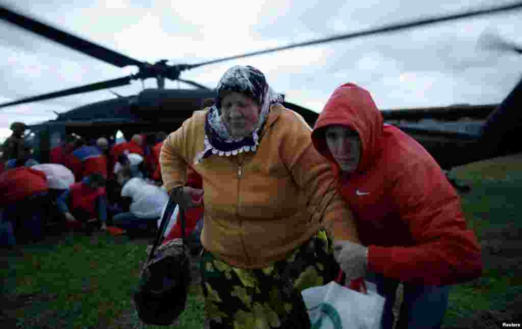 Seorang perempuan dan putranya menjauh dari helikopter Uni Eropa setelah diselamatkan dari desa Serici yang dilanda banjir dekat Zenica, Bosnia (17/5).