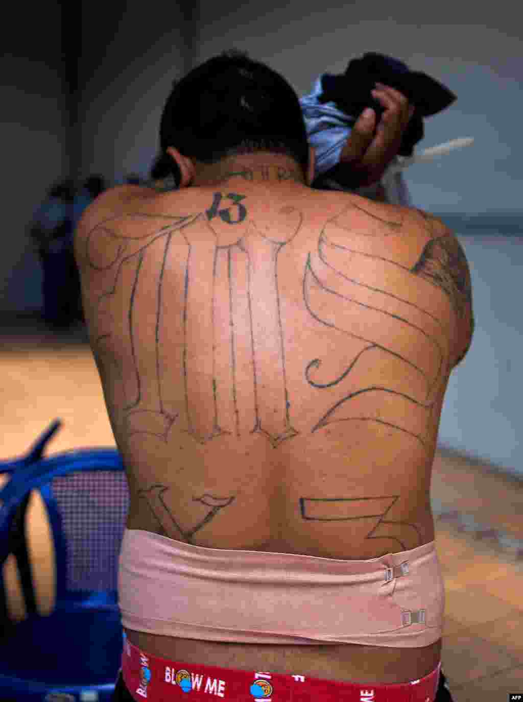 Un supposé membre du gang MS-13 couvre son visage lors d&#39;une arrestation à San Salvador, le 31 janvier 2014.