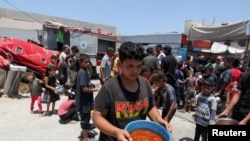 ARCHIVO: Un palestino carga comida preparada en una cocina benéfica, en medio de la escasez de suministros de ayuda, mientras continúa el conflicto entre Israel y Hamás. En Khan Younis, en el sur de la Franja de Gaza, el 19 de junio de 2024.